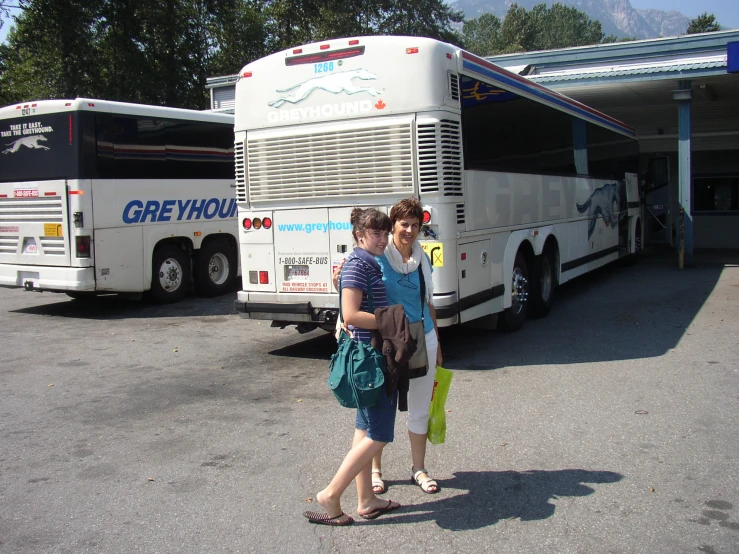 two women are standing in front of a bus