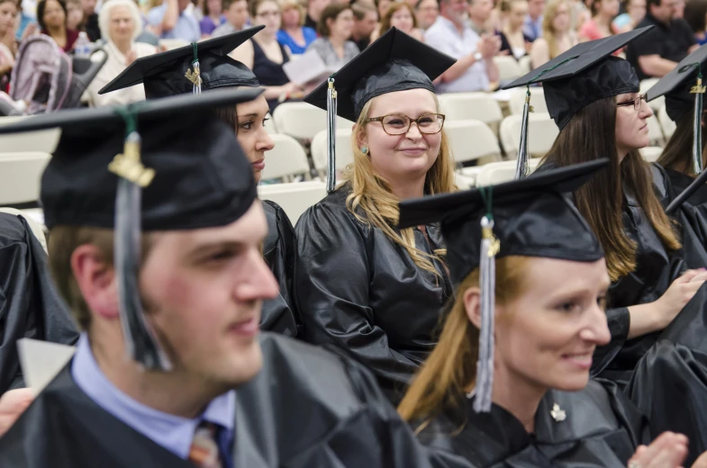 graduates at graduation in black caps and gowns smiling