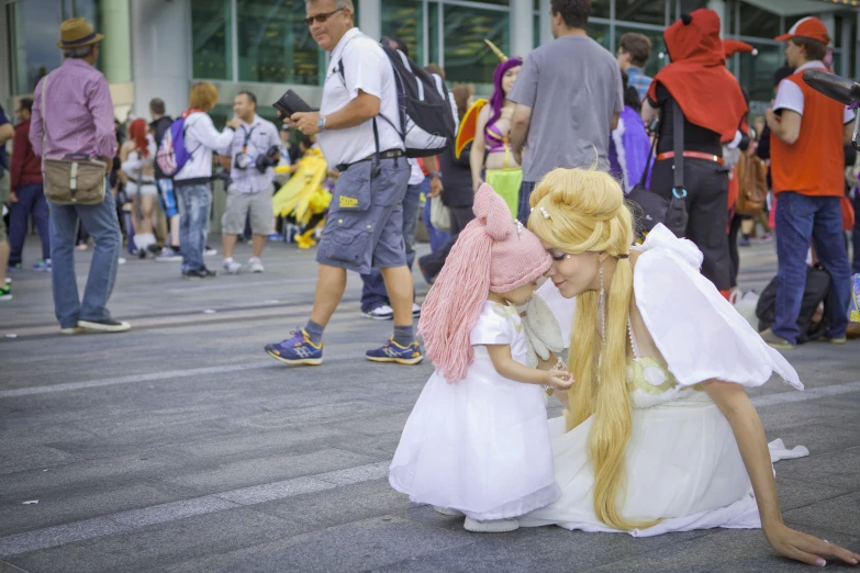 two girls in costumes on the ground next to some people