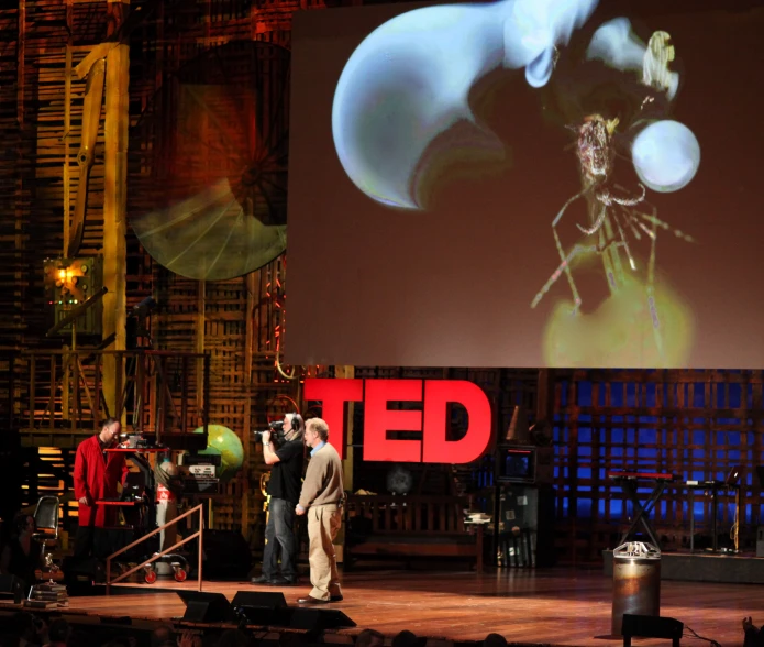 a couple of people on a stage with a large screen behind them