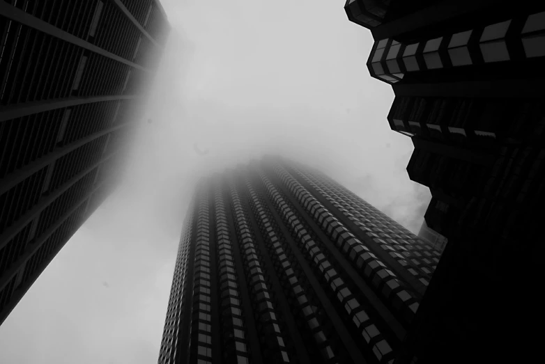 an upward view of two buildings in the fog