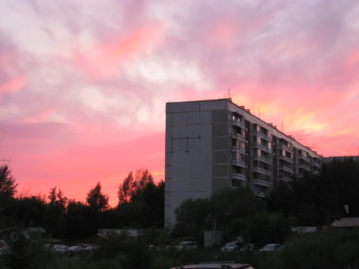 a building near the woods under a sunset sky