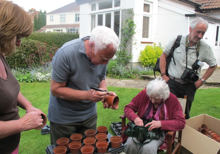 two old men are looking through small brown pots