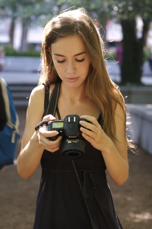 a woman standing outside looking at her cellphone