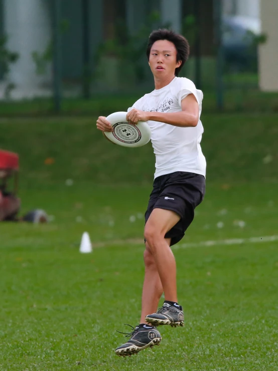 a person in black shorts and a white t - shirt holding a frisbee