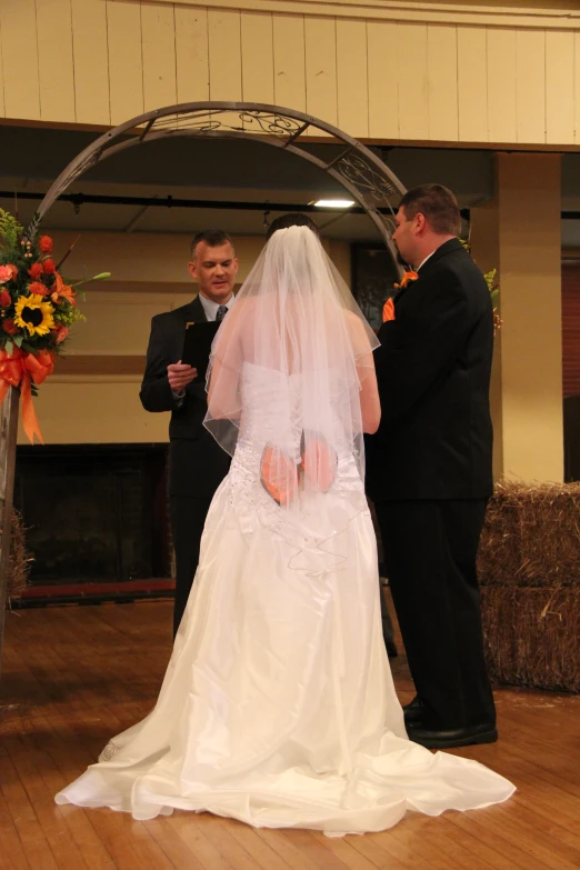 a newly married couple with one of the groom standing behind them