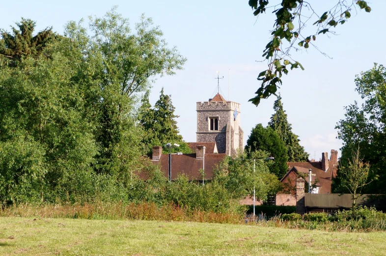 the view of a church through trees and grass