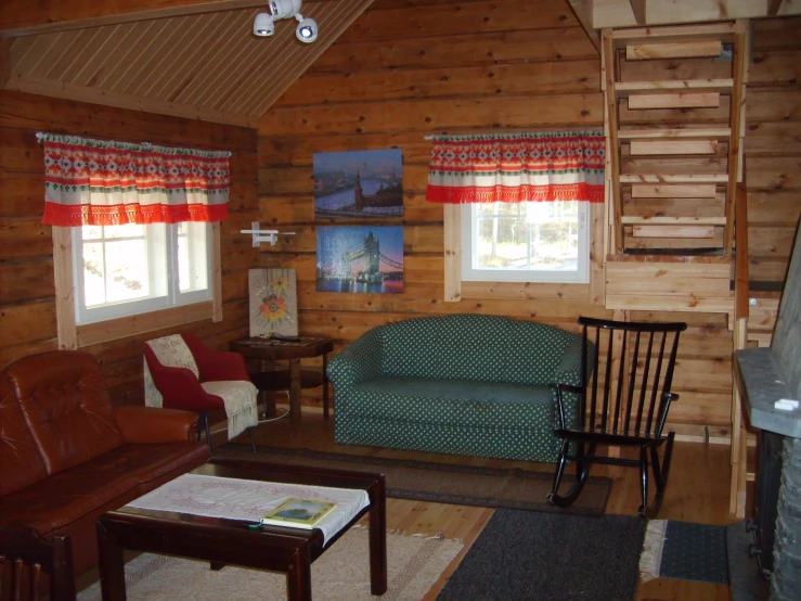 a living room with sofa and chair in wooden cabin