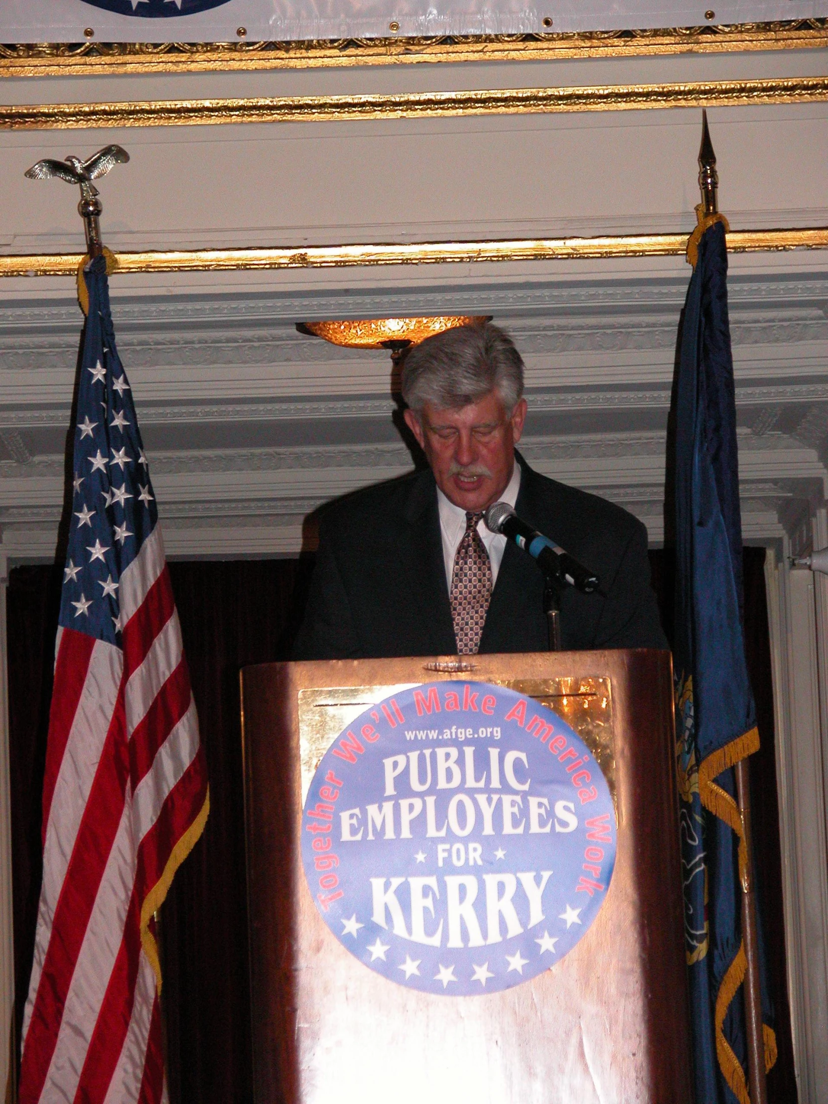 the man is standing at a podium behind an american flag