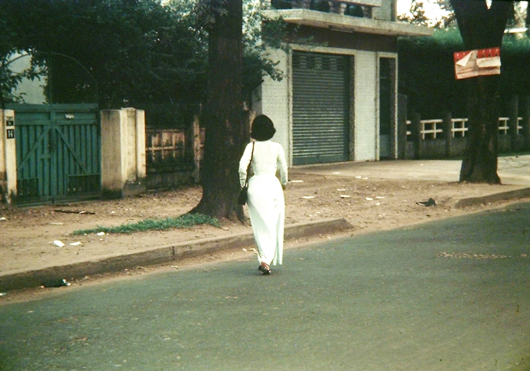 a lady in white on a road near a tree