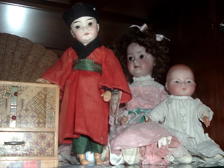 a group of dolls sit on top of a wooden cabinet