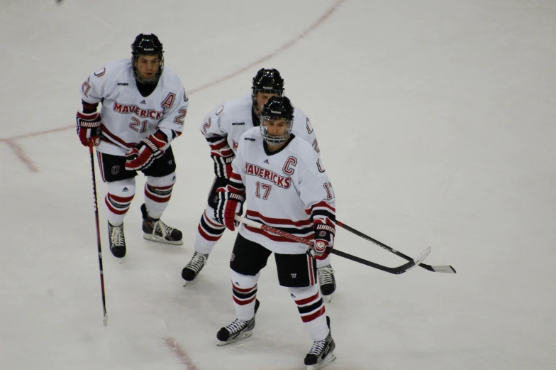 three men playing ice hockey, one wearing uniform