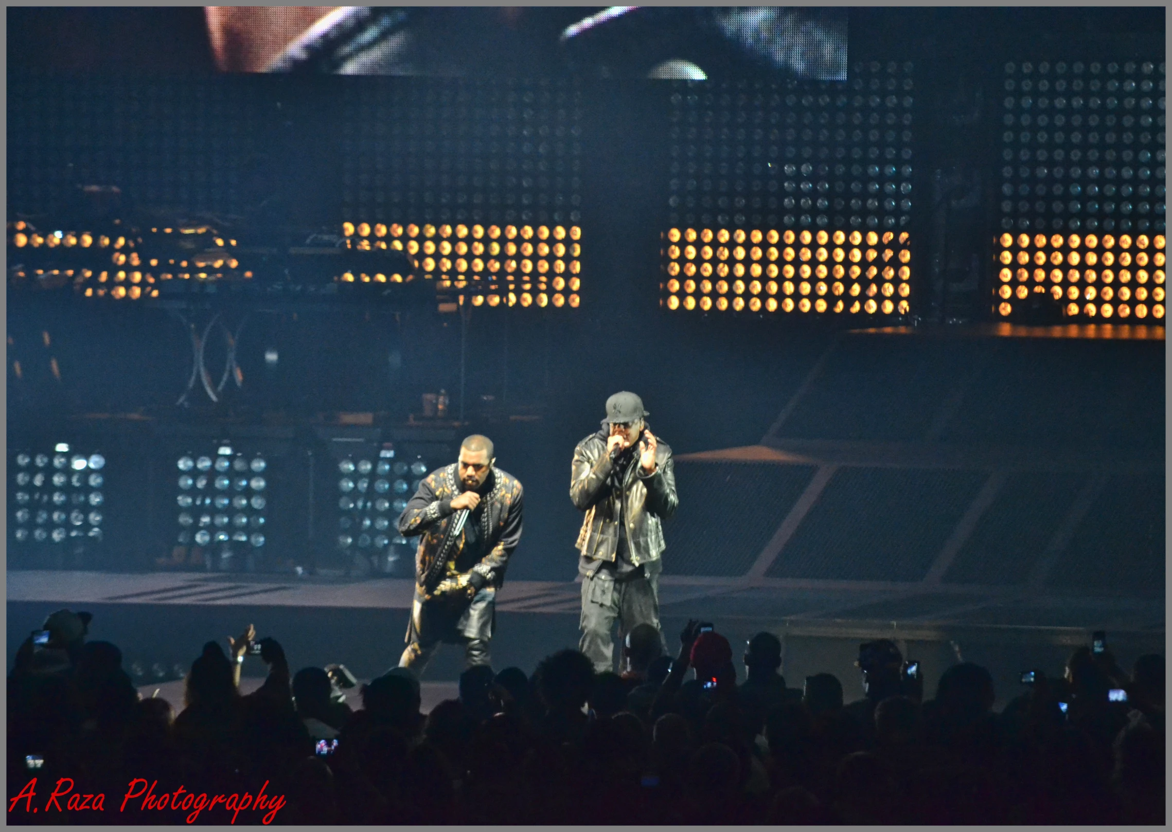 two male singers performing with a large crowd in the background