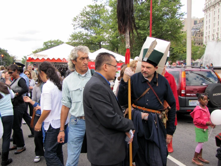 a man is dressed in a green and gold outfit and is talking to another man in black