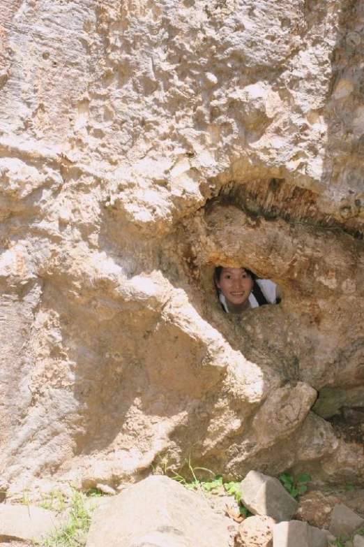the boy looks out of the hole of a rock