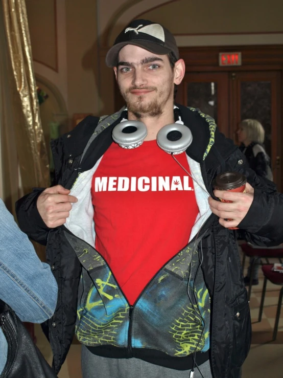 a man wearing a red shirt that says medical holding two headphones on it