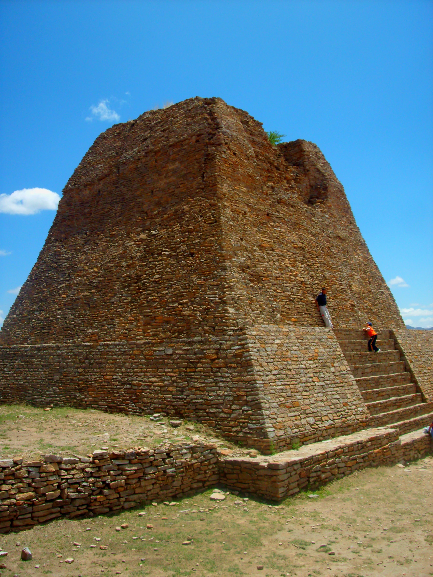 people climbing up a small, stone pyramid