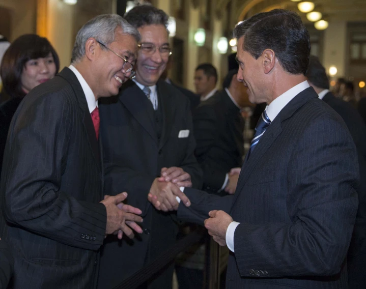 four men dressed in suits smile and talk