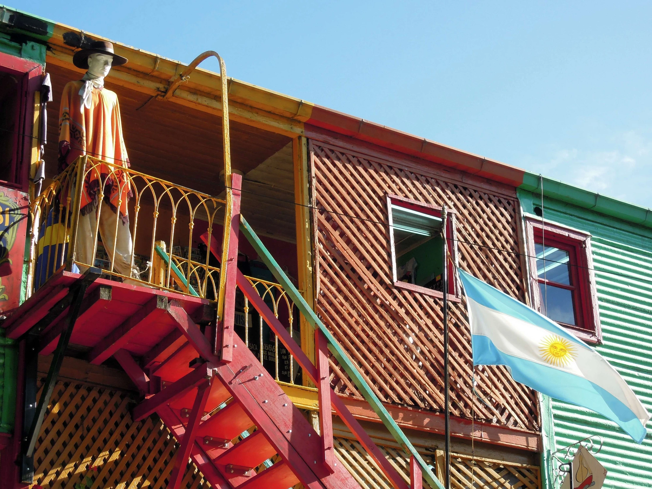 the front of a multi colored building with stairs to upper story