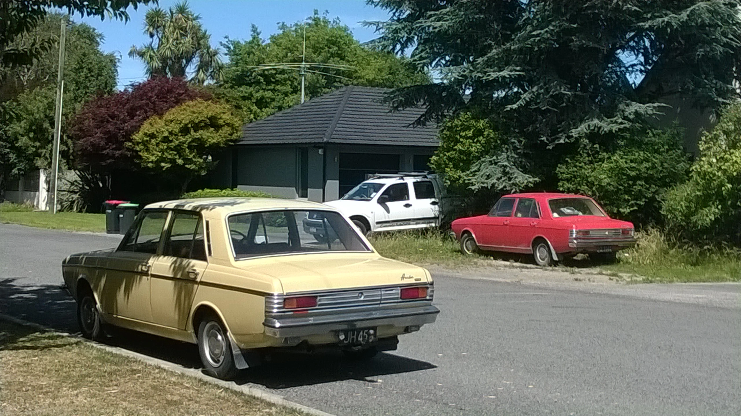 two classic cars parked on the side of a road