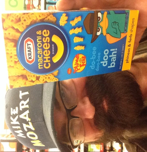 a man in glasses holds up a box of macaroni and cheese