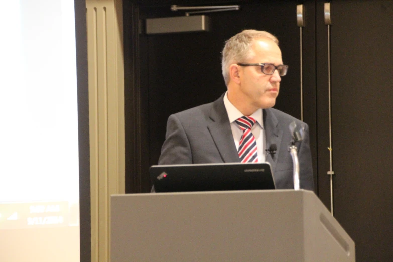 a man in suit and tie speaking at an event