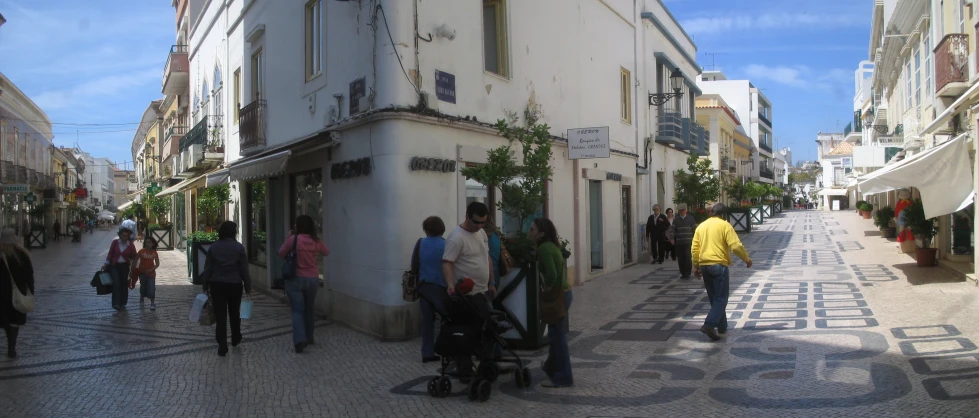 several people walking on the sidewalk next to some buildings