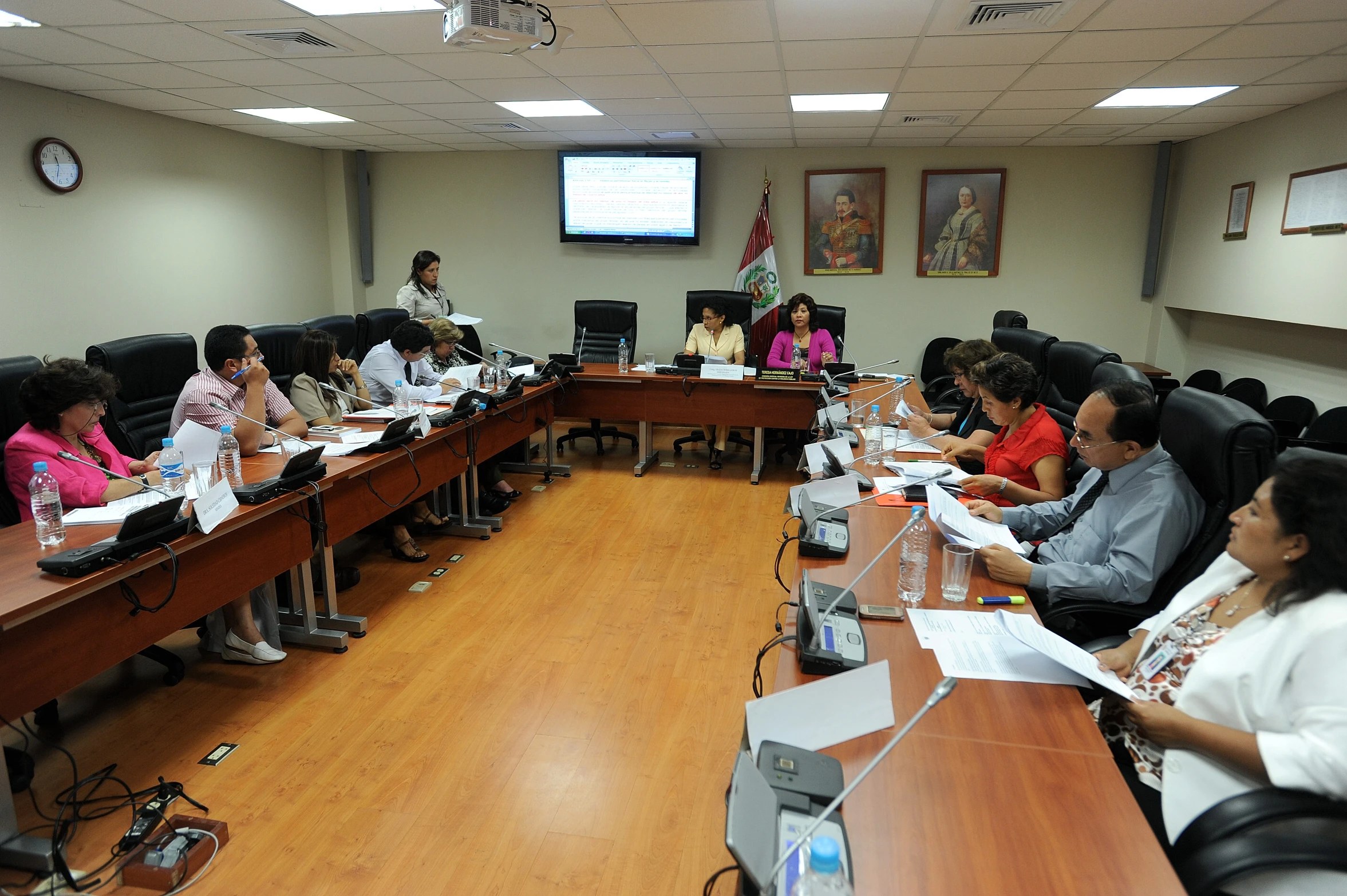 a long boardroom full of people sit at desks