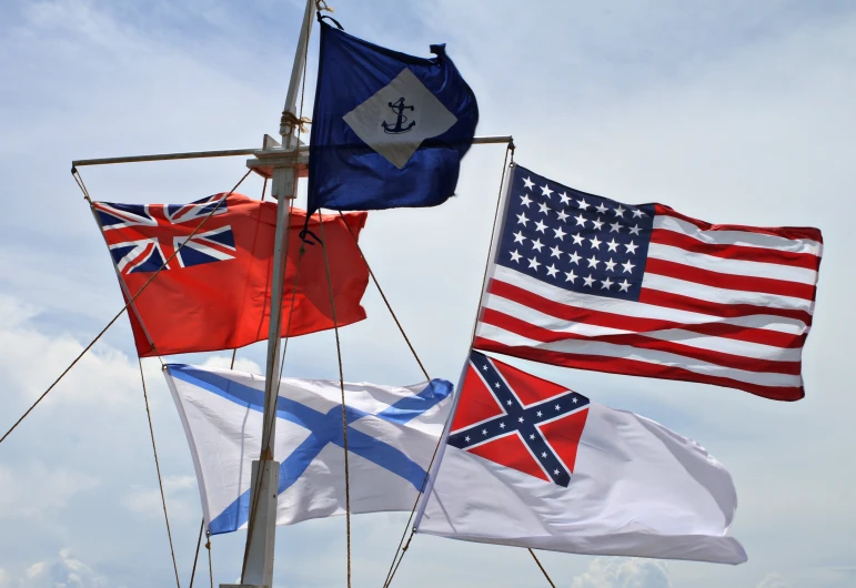 three flags waving in the wind on a blue day