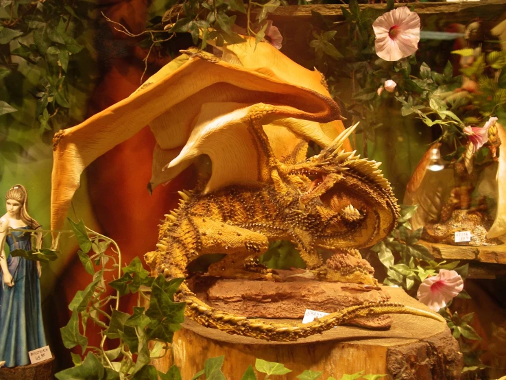 a dragon statue on a tree stump is seen in front of a flower display