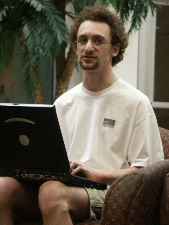 a man sits on the couch and uses a laptop