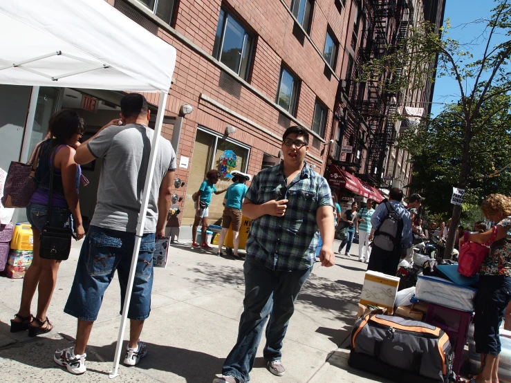 a couple of men stand in front of tents near an apartment building