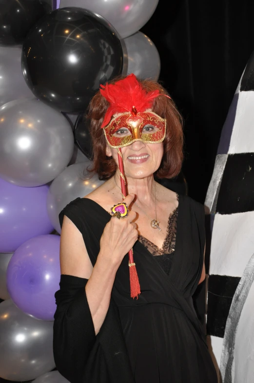 a woman is wearing a red mask and holding a stick