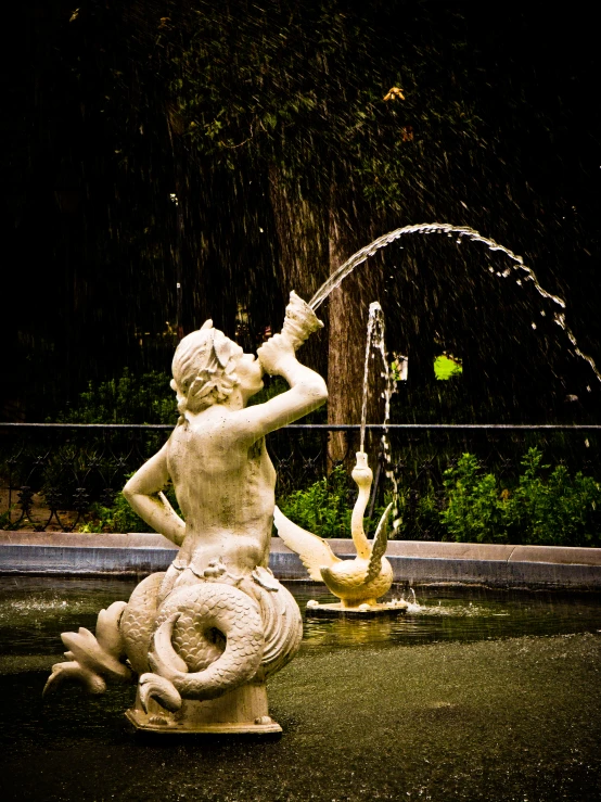 a sculpture with a bird statue holding a water bottle and a dragon statue on it's back, water gushing from it's mouth