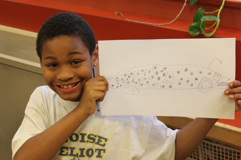 a little boy is holding a white paper with drawings on it