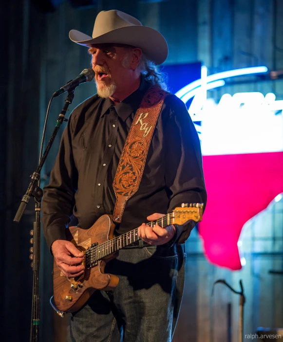 man in cowboy hat playing guitar on stage