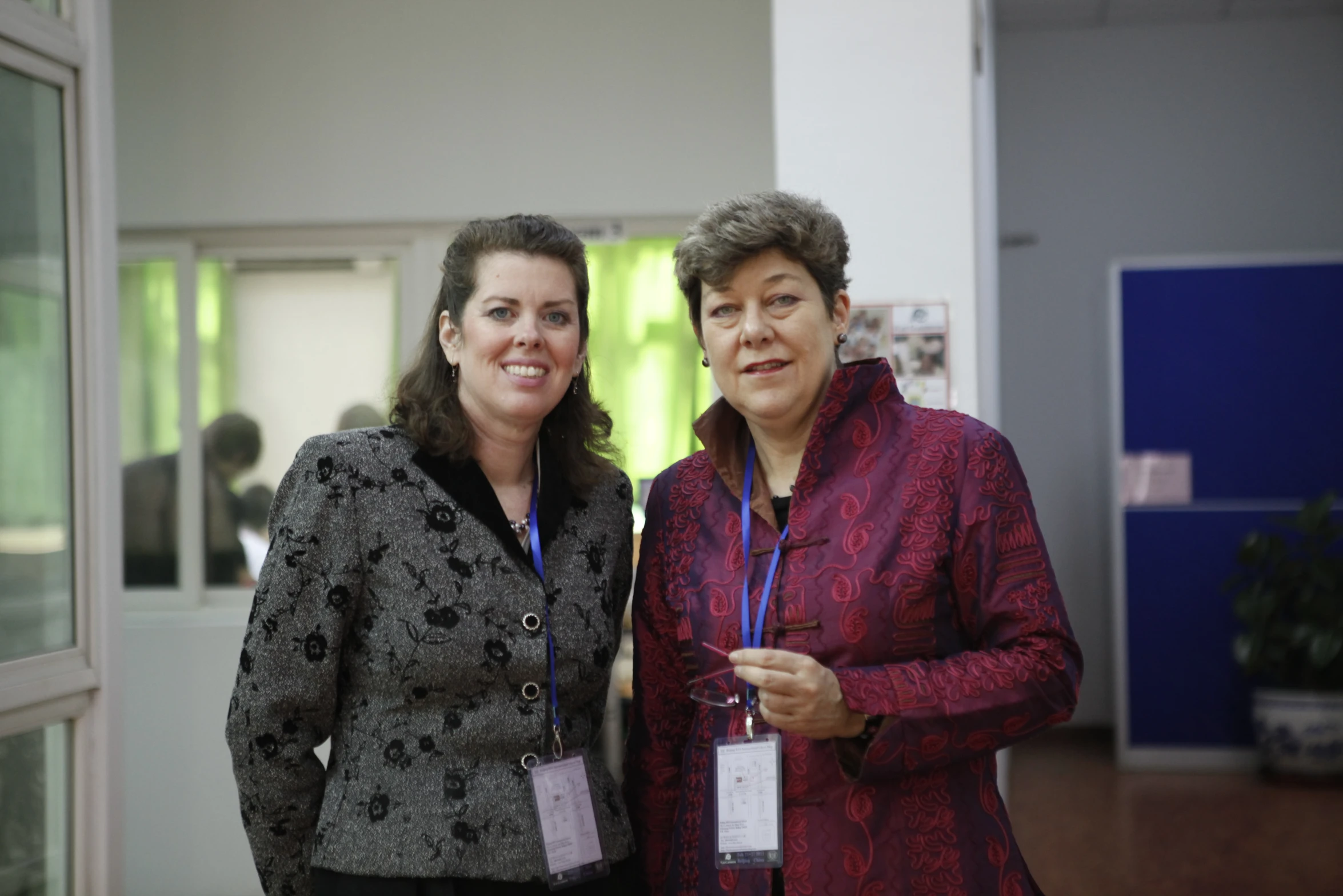 two women standing next to each other, each wearing jackets