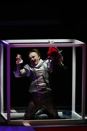 the male performer has his hand raised in a box