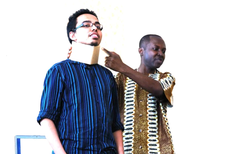 two men standing up against a white wall