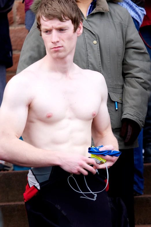 shirtless young man holding items in his hand at outdoor event