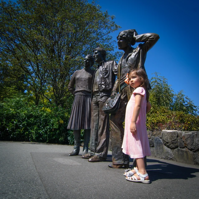 a small girl stands in front of statues