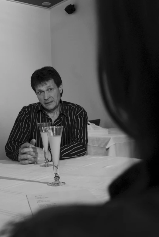 a man is sitting at a table with a glass of alcohol