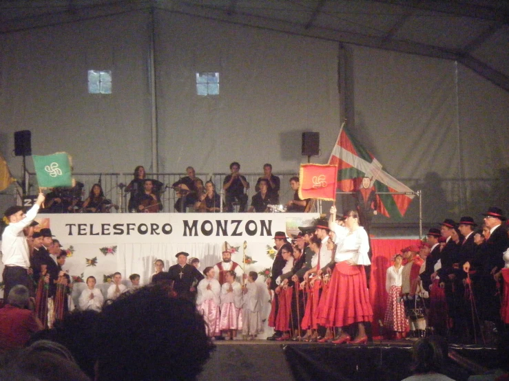 several performers on stage with flags at indoor event