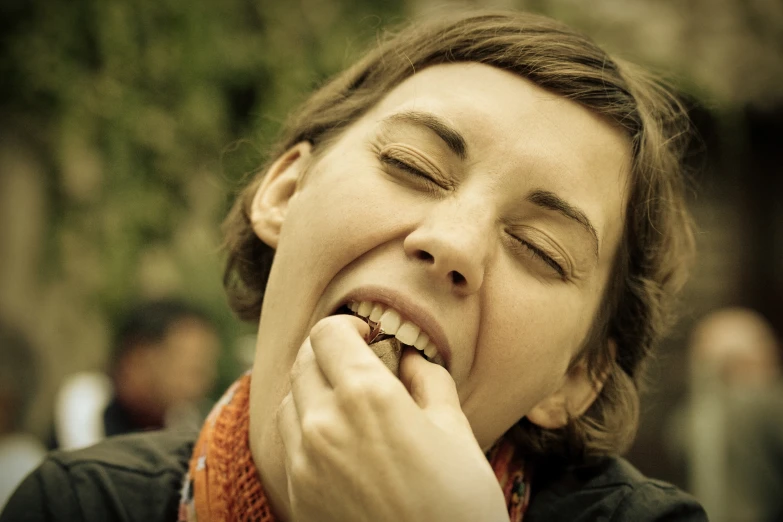 a woman holds her face up to the side while she has her teeth open