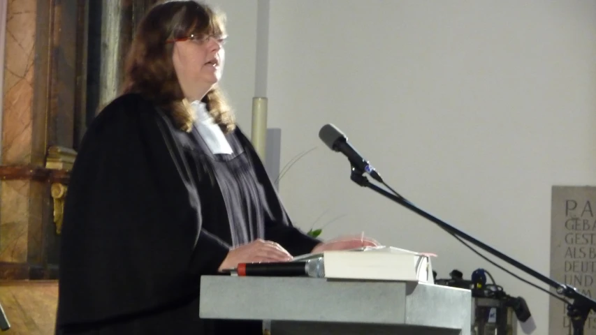 a woman wearing glasses standing next to a microphone