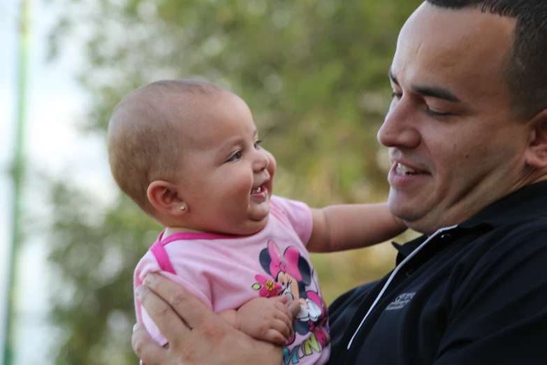 an adult and child smiling together while being held by the man