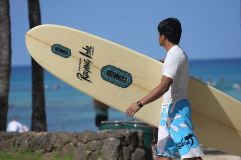 man walking with surfboard down the beach near water