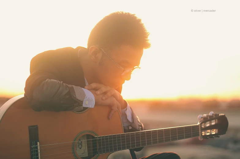 a man playing the guitar at sunset on the beach