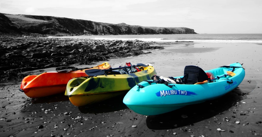 three kayaks lined up on a beach near the water