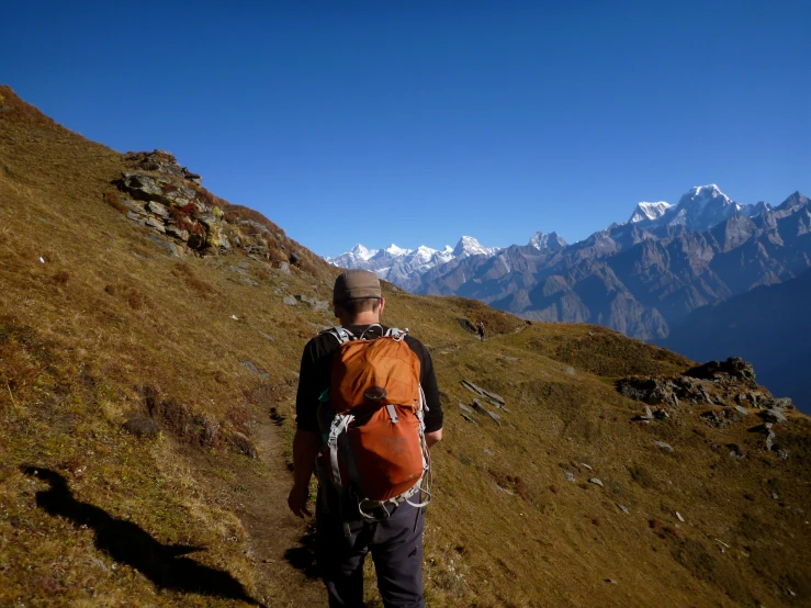 a man hiking uphill on top of a grass covered slope